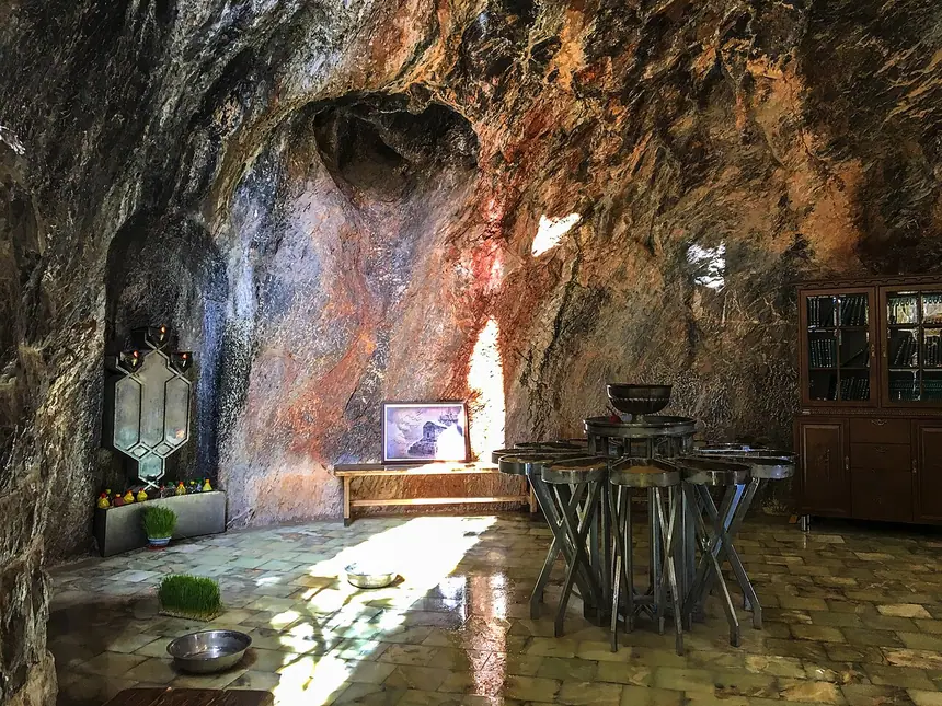 Bên trong hang thờ Pir-e Sabz (Chak Chak): vách đá ám khói, nền lát đá, giá lửa bằng kim loại ở giữa. Ảnh chụp năm 2017.