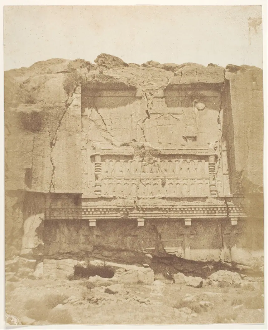 Một lăng vua đục vào vách núi ở Persepolis, ảnh của Luigi Pesce chụp năm 1858. Tầng trên vẫn là cảnh quen thuộc: vua, bệ lửa và hình người có cánh. Bộ sưu tập Bảo tàng Metropolitan.