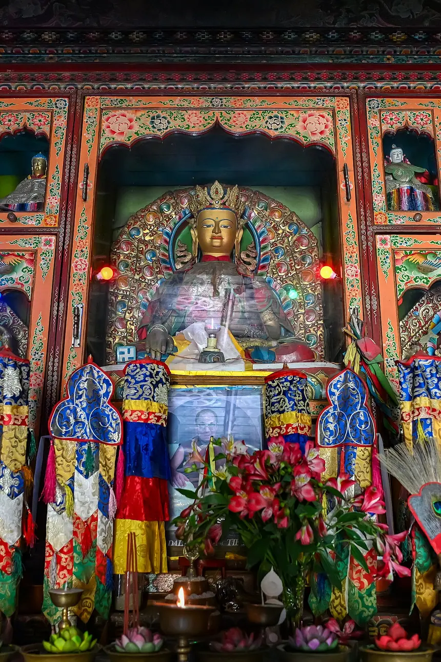 Pho tượng giữa ban thờ tu viện Bön ở Kewzing, Sikkim, có đội mũ miện, phía trước là hoa, đèn và phẩm cúng. Trang tệp gốc không ghi tên vị được thờ.