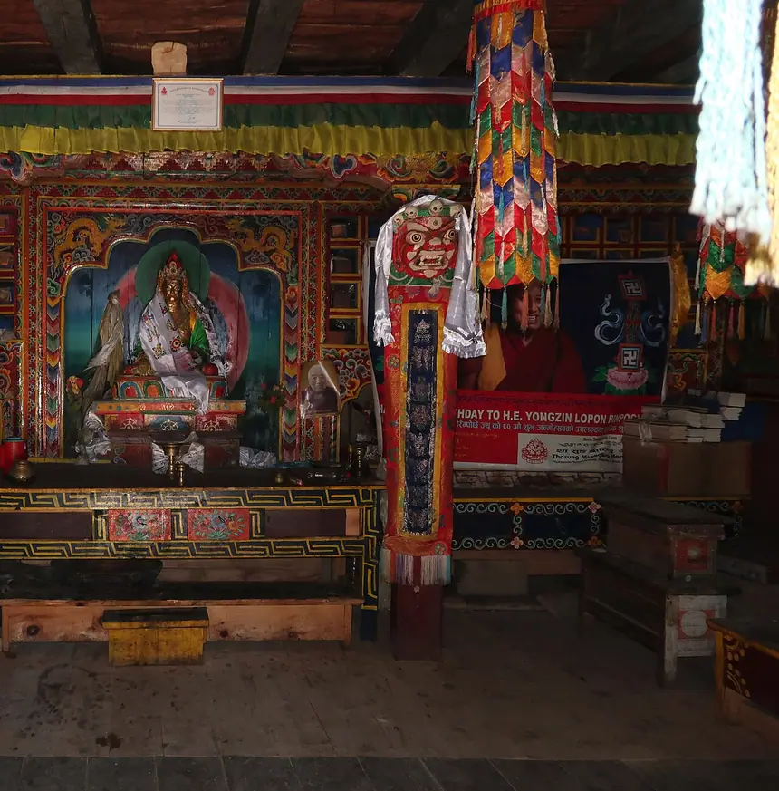 Bên trong tự viện Bön ở Ringmo, Dolpo, Nepal: tượng trong khám sơn màu, bàn cúng bằng gỗ, tràng phan treo trước ban thờ. Ảnh chụp năm 2019.