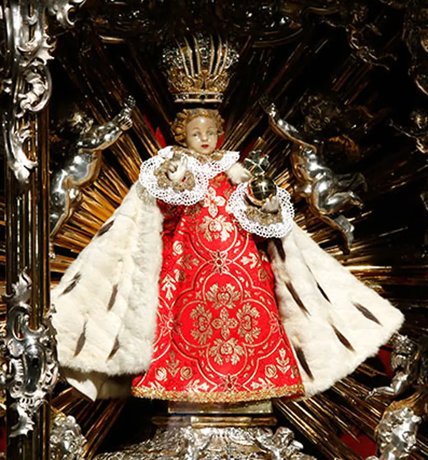 Tượng Chúa Hài Đồng Praha: gỗ phủ sáp, cao 48 phân, mặc áo choàng thêu và đội triều thiên. Nhà thờ Đức Mẹ Chiến Thắng, Praha, Cộng hòa Séc. Ảnh chụp năm 2012.