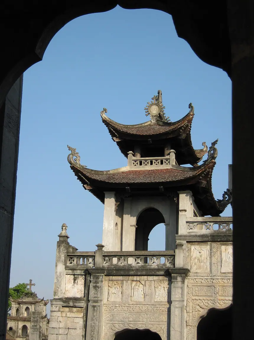 Một tháp đá mái cong trong quần thể nhà thờ Phát Diệm, Ninh Bình, nhìn qua vòm cửa.