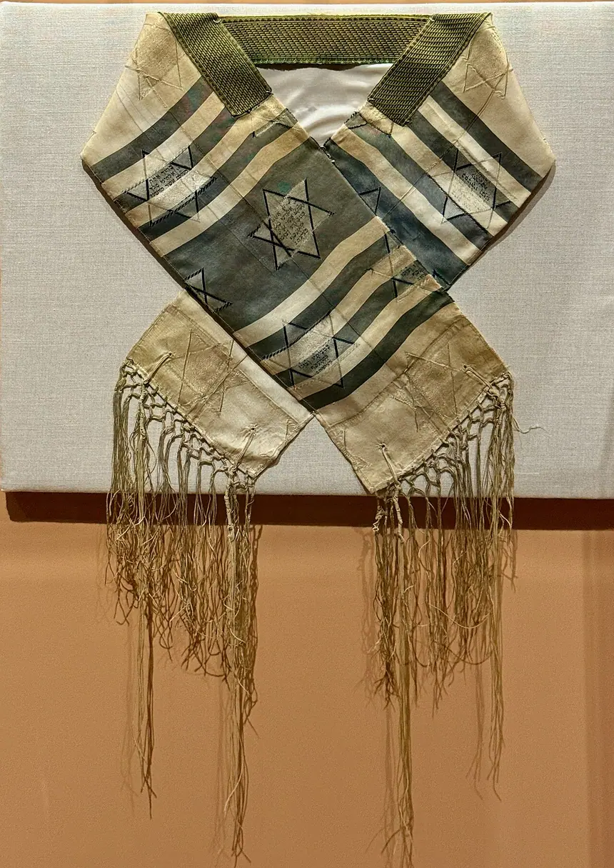Một tấm khăn choàng cầu nguyện (tallit) có sọc và tua, hiện vật bảo tàng. Trang ảnh gốc không ghi tên bảo tàng và niên đại.