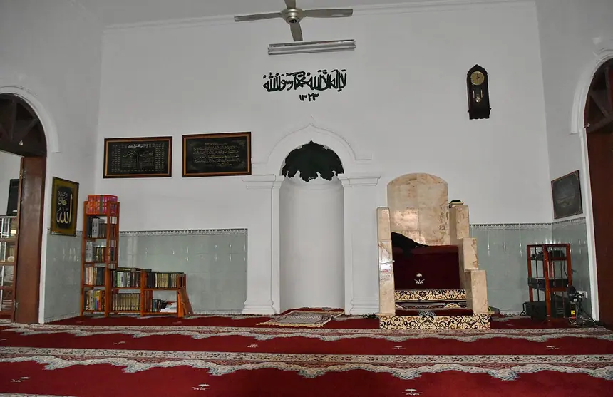 Bên trong thánh đường Al-Noor, phố Hàng Lược, Hà Nội: hốc mihrab, bục minbar và mấy khung chữ trên tường trắng. Ảnh chụp năm 2017.