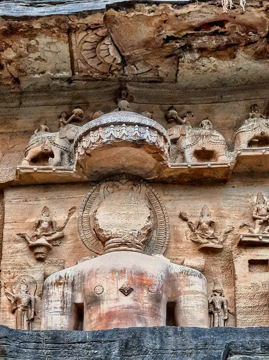 Tượng Jina ngồi tạc vào vách đá, nhóm Gopachal bên thành Gwalior, Madhya Pradesh, thế kỷ 14 tới 15. Phần đầu tượng đã hư hại.
