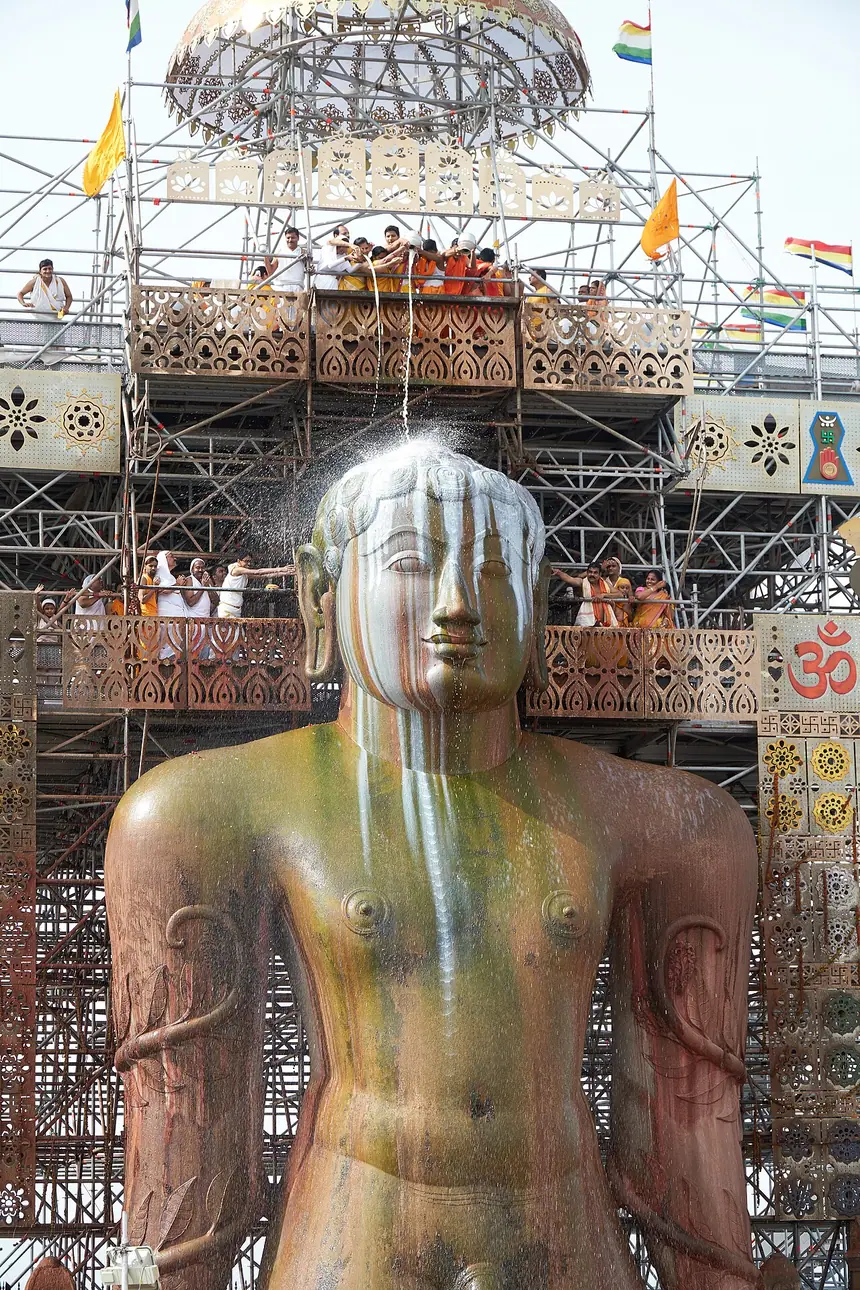 Lễ Mahamastakabhisheka (đại lễ tắm tượng từ đỉnh đầu) ở Shravanabelagola, năm 2018. Giàn giáo dựng sau tượng để dâng các thứ nước lễ từ trên cao. Tượng không y phục, theo truyền thống Digambara.