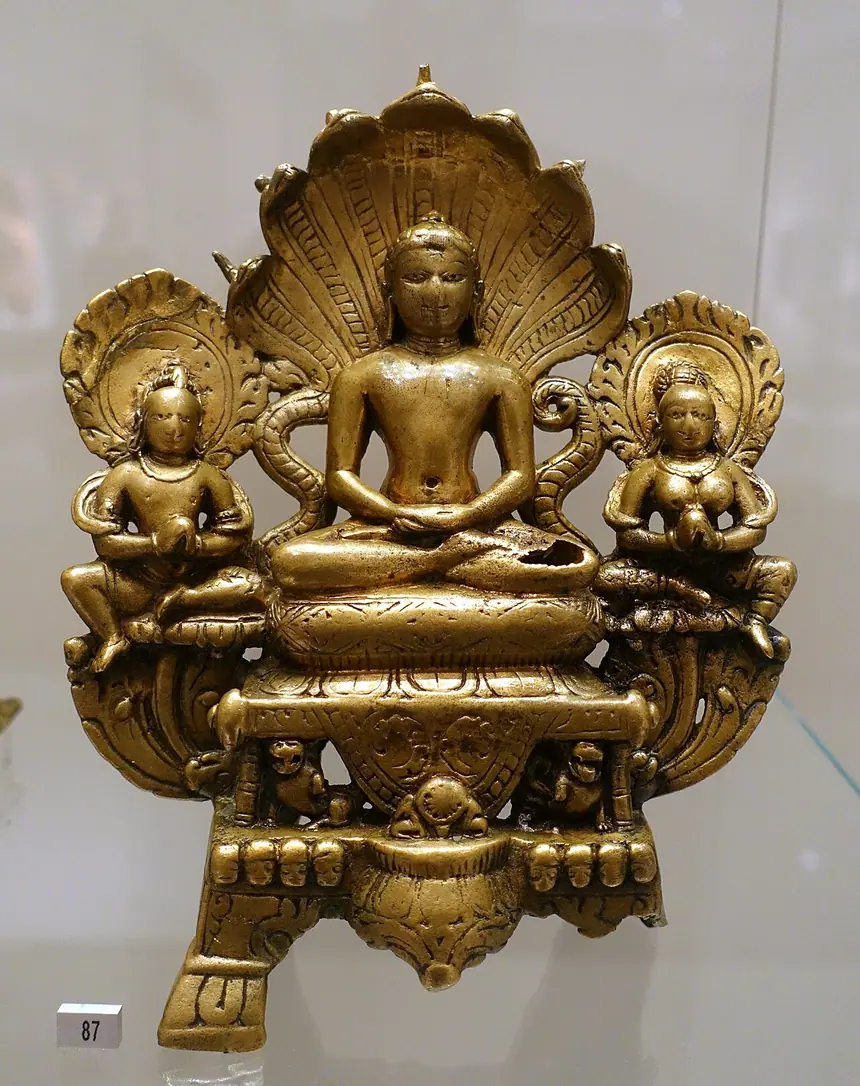 Parshvanatha ngồi dưới tán rắn thần nhiều đầu, hai bên có vị hầu. Đồng thau, Gujarat, thế kỷ 8. Bảo tàng Dân tộc học Berlin.