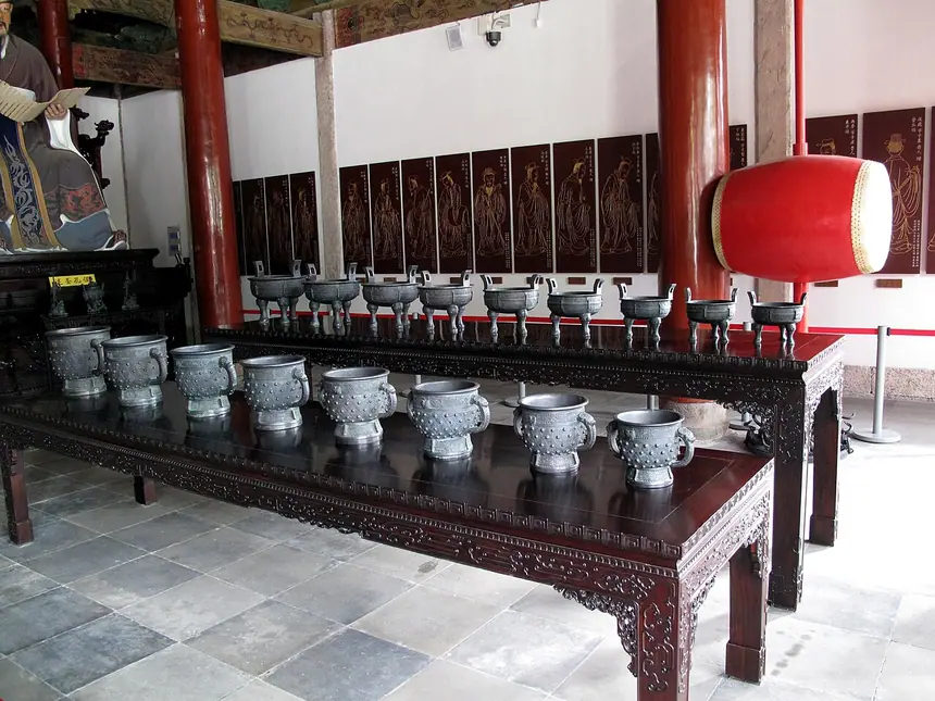 Hàng đồ tế bằng đồng và chiếc trống lớn ở Khổng miếu Hàng Châu. Trên tường phía sau là bản sao tranh các học trò của Khổng Tử. Ảnh chụp năm 2009.