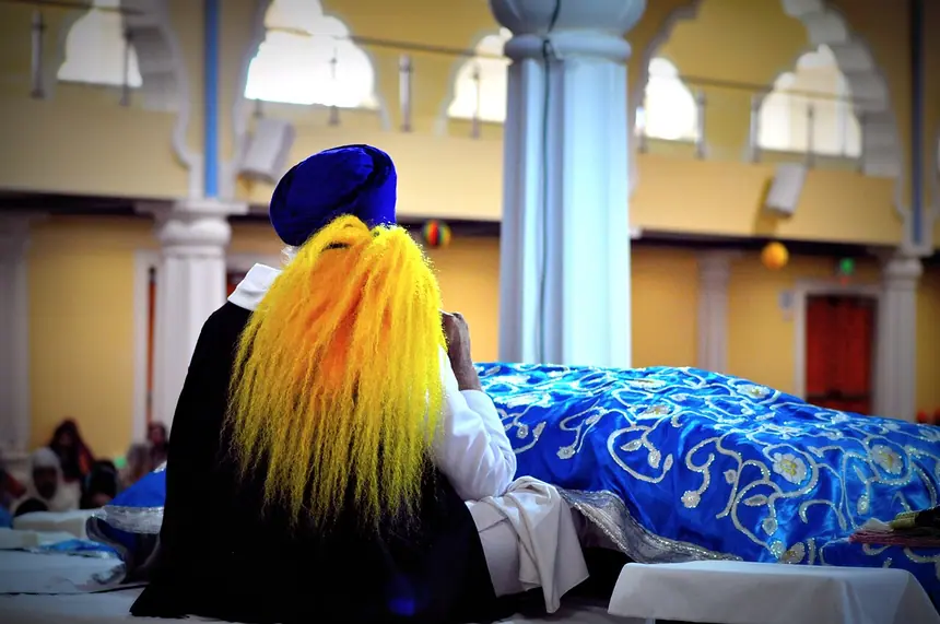 Phất chaur trên Guru Granth Sahib: Kinh đang được phủ khăn rumala màu lam, người hầu Kinh cầm cây phất màu cam. Ảnh chụp từ phía sau, năm 2013.