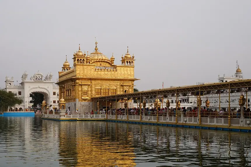 Harmandir Sahib, tức Đền Vàng, giữa hồ nước ở Amritsar, nối với bờ bằng một lối đi lát đá. Ảnh chụp năm 2018.