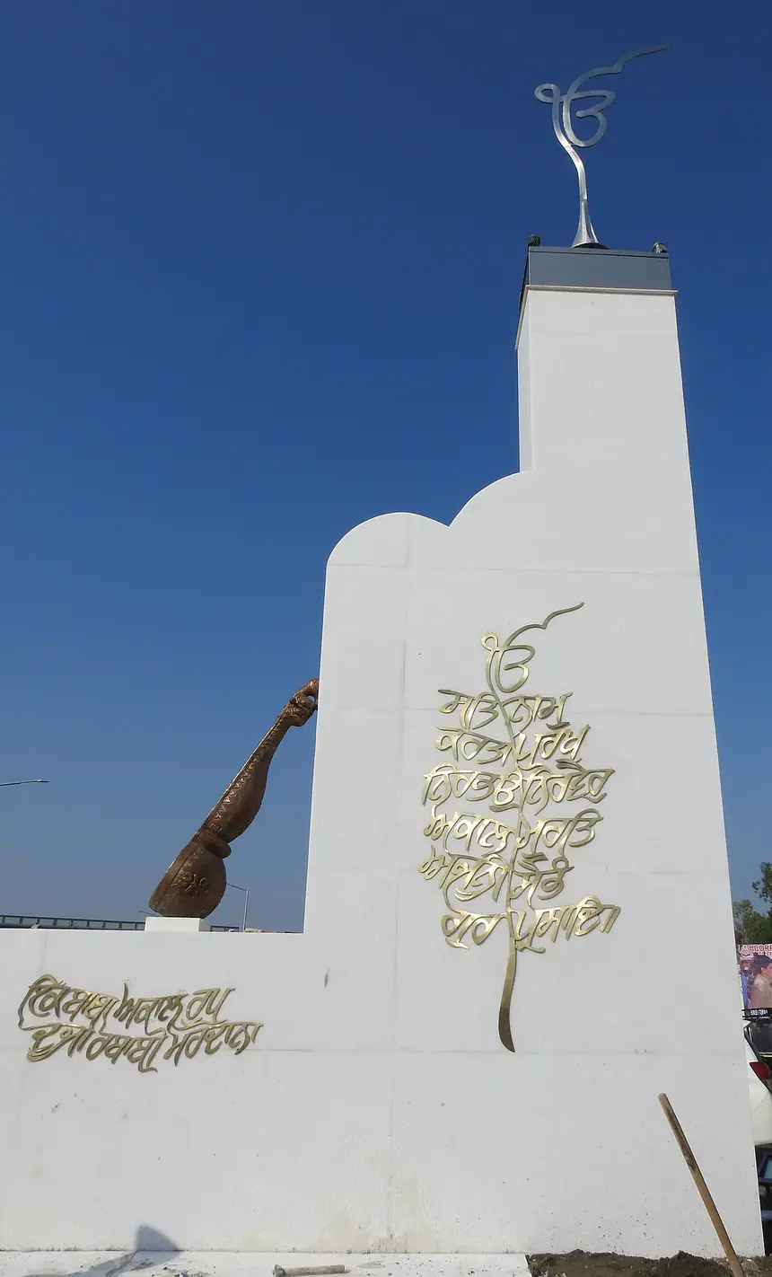 Chữ Ik Onkar trên đỉnh và trên mặt một công trình mới dựng ở lối vào Hành lang Kartarpur, phía Dera Baba Nanak, Ấn Độ. Công trình hiện đại, ảnh chụp năm 2019.