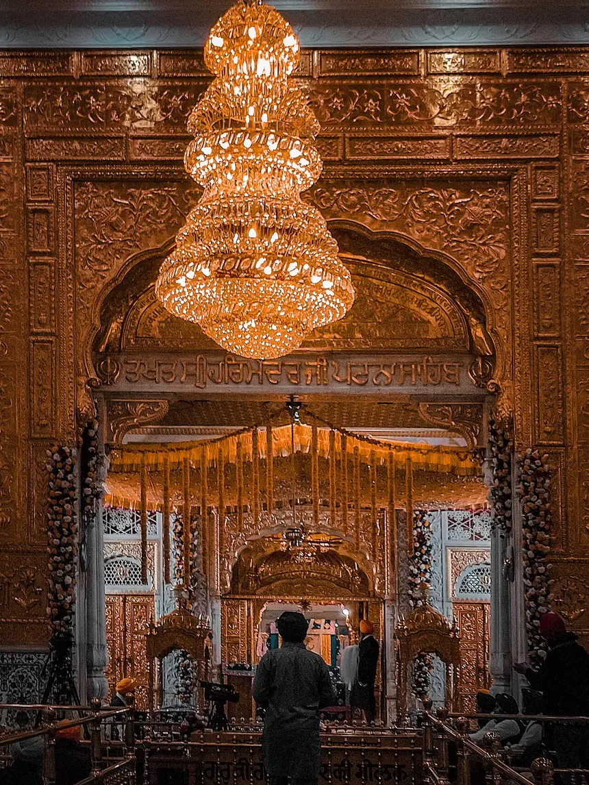 Bên trong Takht Sri Patna Sahib, Patna, bang Bihar: vách dát kim loại vàng chạm nổi, đèn chùm, gian trong là nơi tôn trí Kinh. Ảnh chụp năm 2022.