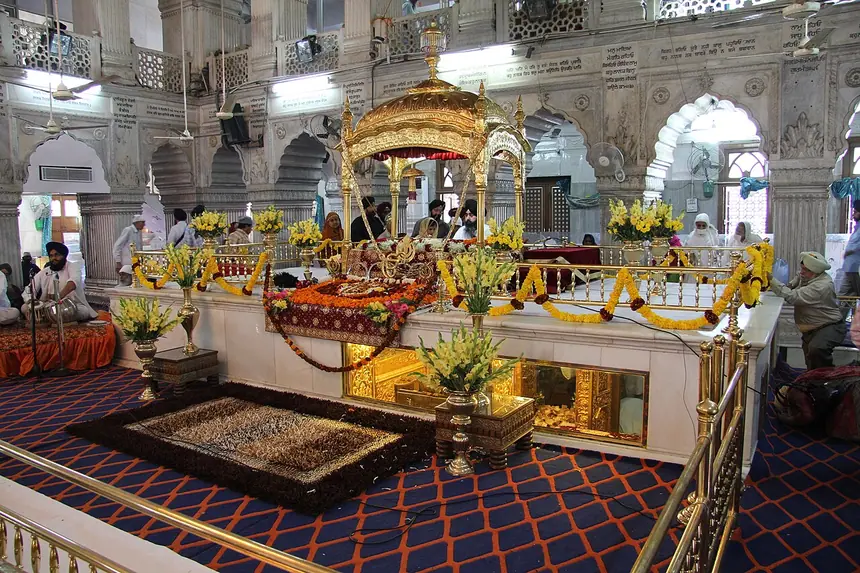 Mặt trước gian chính của Gurdwara Sis Ganj, Delhi cổ, Ấn Độ: palki tôn trí Guru Granth Sahib, bục chính kết hoa tươi. Ảnh chụp năm 2011.