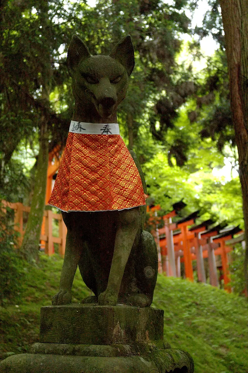 Tượng cáo bằng đá đeo yếm đỏ bên lối đi ở đền Fushimi Inari, Kyoto. Ảnh năm 2008.