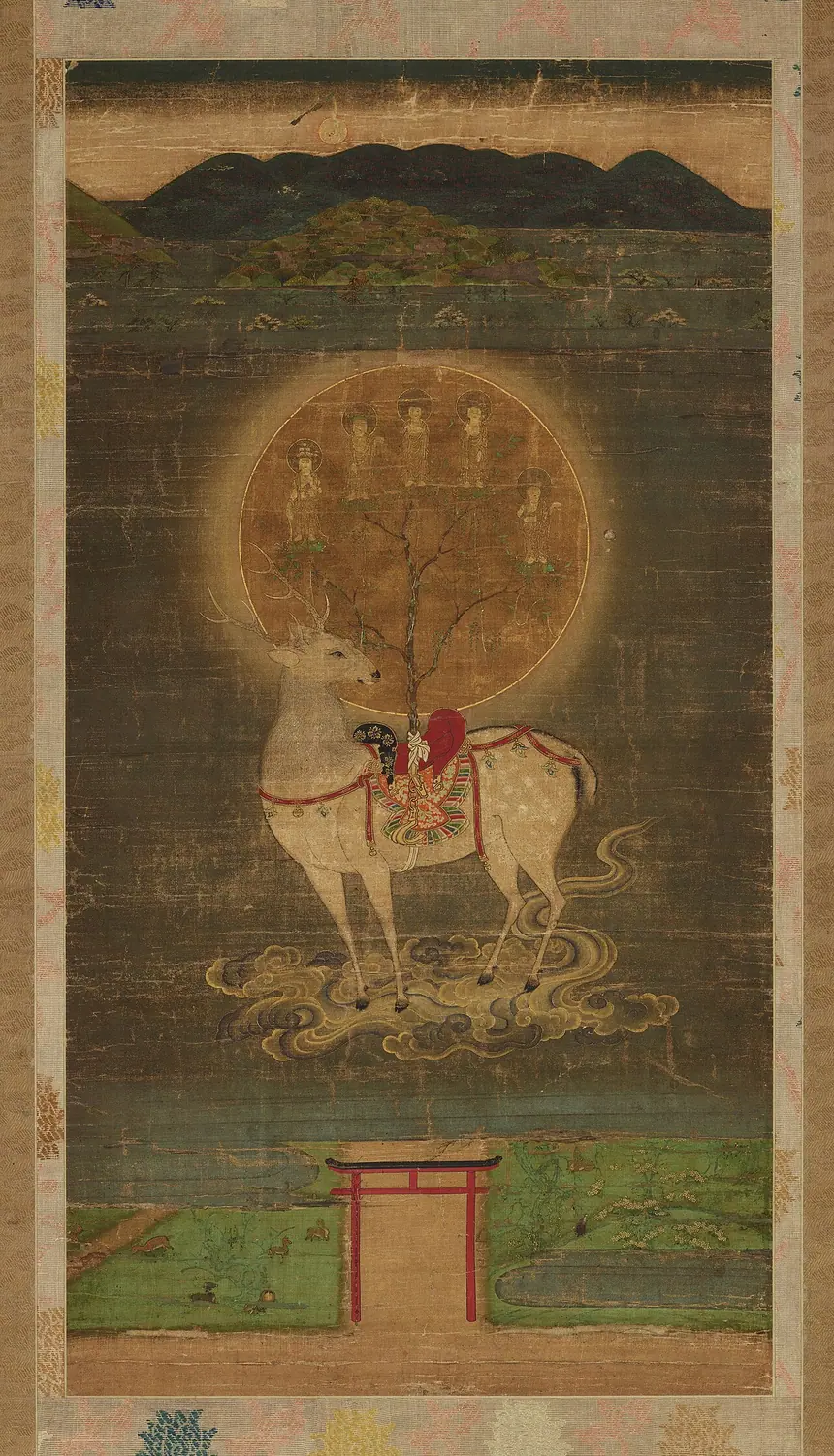 Mạn đà la hươu Kasuga: con hươu mang yên, trên yên dựng cành sakaki đỡ một vầng tròn, phía dưới là cổng torii. Tranh lụa, theo trang tệp là cuối thế kỷ 13. Bảo tàng Quốc gia Nara.