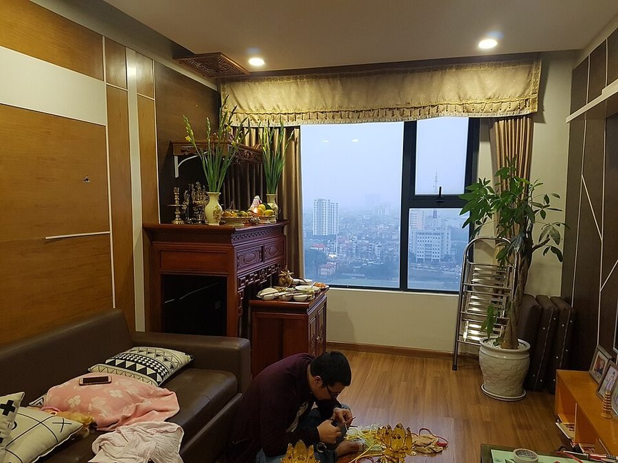 Modern Vietnamese apartment ancestral altar with lower offering table. Clean contemporary Vietnamese apartment setup pairing an elevated wooden ancestral altar with a dedicated lower front cabinet pulled out to hold ceremonial meal trays.